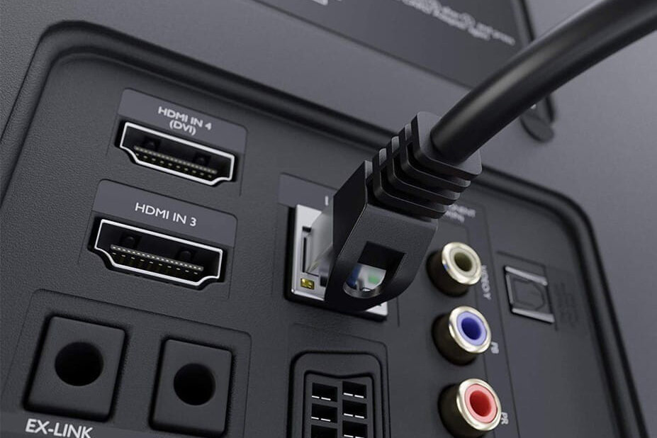 Obraz przedstawia panel złącz z wtyczką kabla ethernet podłączoną do portu RJ-45. Widoczne są również złącza HDMI oznaczone jako HDMI IN 3 i HDMI IN 4 (DVI), a także złącza audio i inne porty.