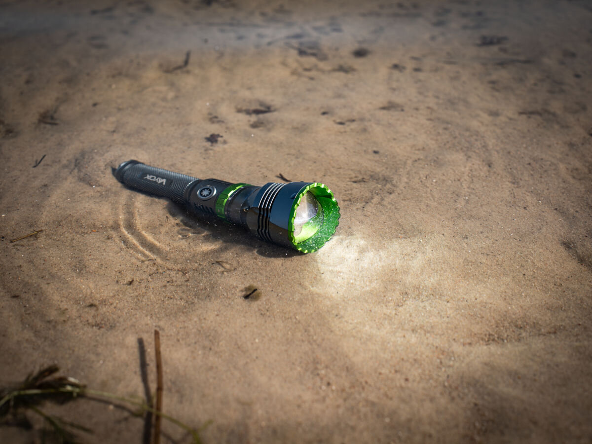 Latarka taktyczna VAYOX VA0363, Wytrzymałość i wodoodporność, Latarka włączona i do połowy zanurzona na brzegu basenu wodnego