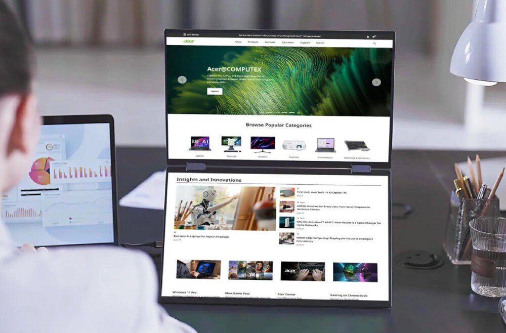 Monitor ACER PD163QT Osoba siedząca tyłem przy biurku, przed którą stoją dwa pionowe ekrany wyświetlające stronę internetową oraz mniejszy ekran laptopa po lewej