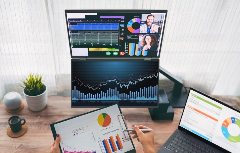 Monitor ACER PD163QT Widok z góry na biurko z laptopem, dokumentami z wykresami oraz dwoma pionowymi ekranami zamontowanymi na uchwycie biurkowym nad blatem