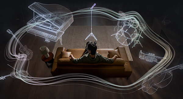 Mężczyzna na kanapie otoczony zarysem instrumentów 360 Audio: mikrofon, perkusja, trąbka, wiolonczela, skrzypce, gitara, fortepian.