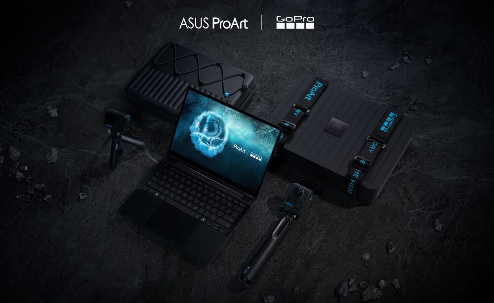 Na ciemnym tle znajduje się otwarty laptop z widocznym ekranem, na którym wyświetla się logo \'ProArt\'. Obok laptopa leżą akcesoria, w tym kamery i walizki, a w górnej części obrazu widoczne są logotypy \'ASUS ProArt\' i \'GoPro\'.