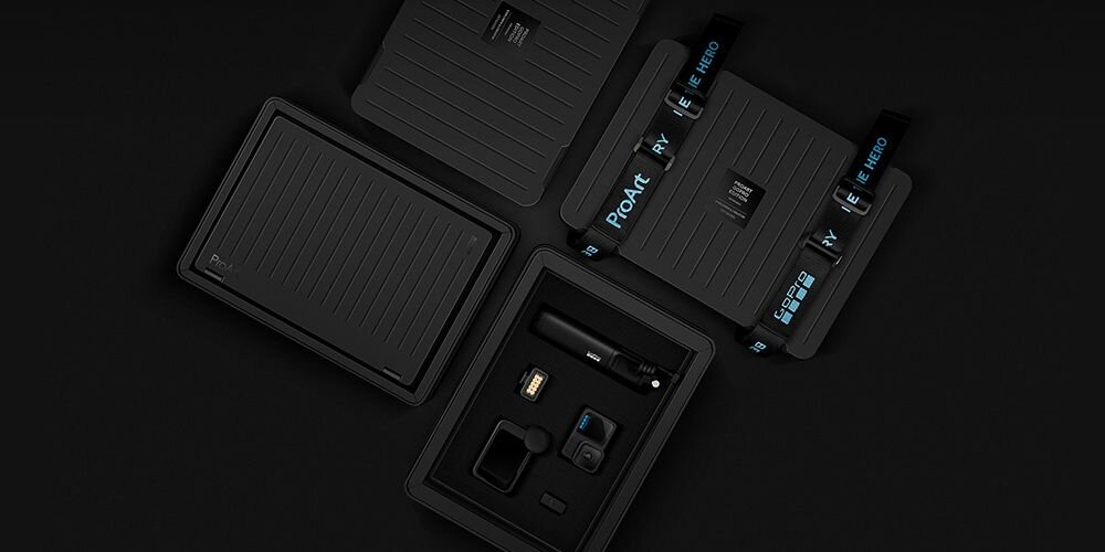 Na obrazie widoczne są cztery czarne, prostokątne pudełka z napisem \'ProArt\' oraz różnymi akcesoriami w środku, w tym kamera i inne drobne elementy. Pudełka mają teksturowaną powierzchnię i są otwarte, ukazując zawartość.