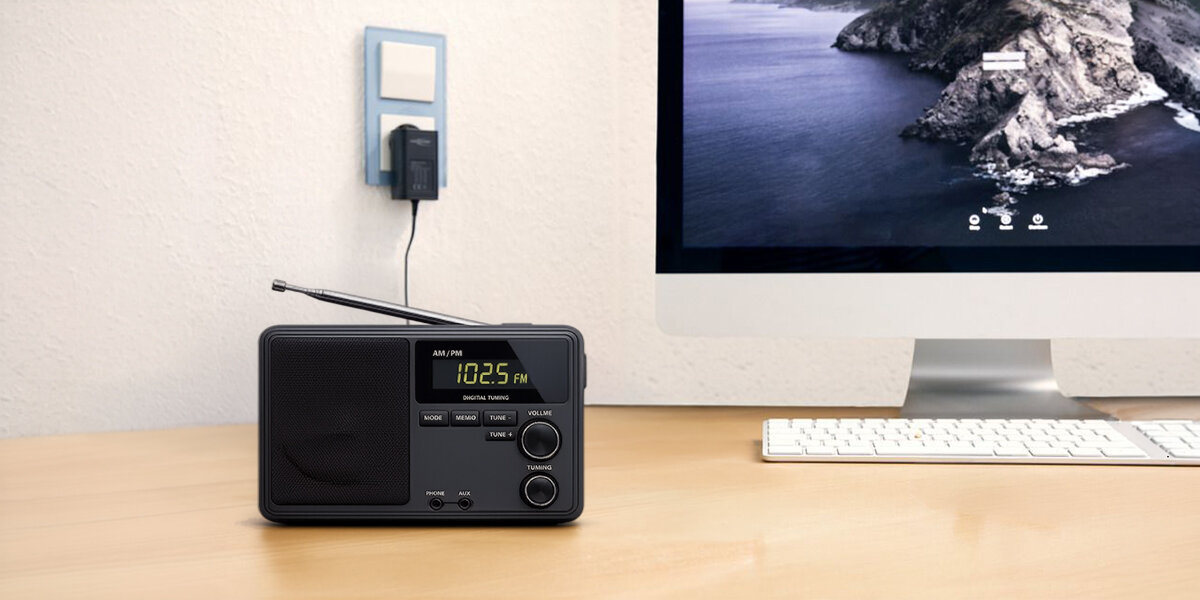 Zasilacz ANSMANN APS zasila radio stojące na biurku obok monitora i klawiatury w domowym środowisku pracy
