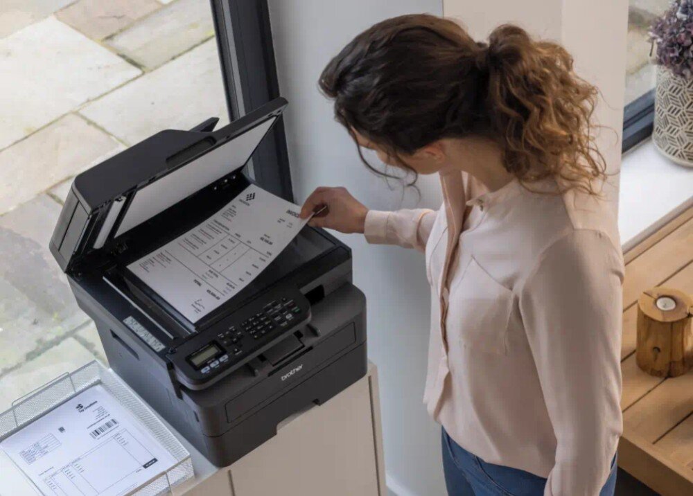 Urządzenie wielofunkcyjne BROTHER MFC-L2802DW widok z góry na kobietę układającą kartkę na powierzchnię skanera rozdzielczość optyczna automatyczny podajnik funkcje