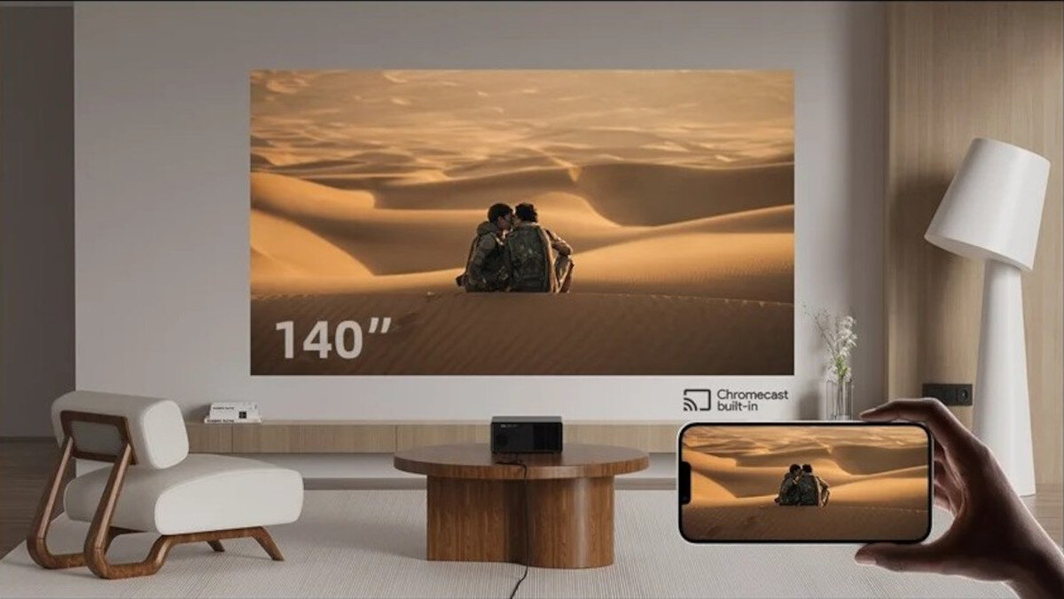 Projektor WANBO X5 Pro New 2GB RAM HDMI USB WiFi 2.4G 5G Chromecast, projektor stojący na stoliku wyświetlający obraz na ścianie, ręka trzymająca smartfona