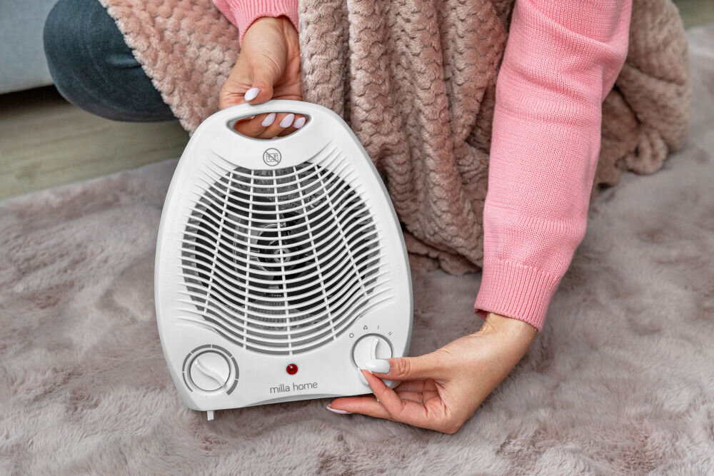 Termowentylator MILLA HOME MFH103 Zbliżenie na dłoń ustawiającą tryb pracy na prawym pokrętle termowentylatora MILLA HOME MFH103.