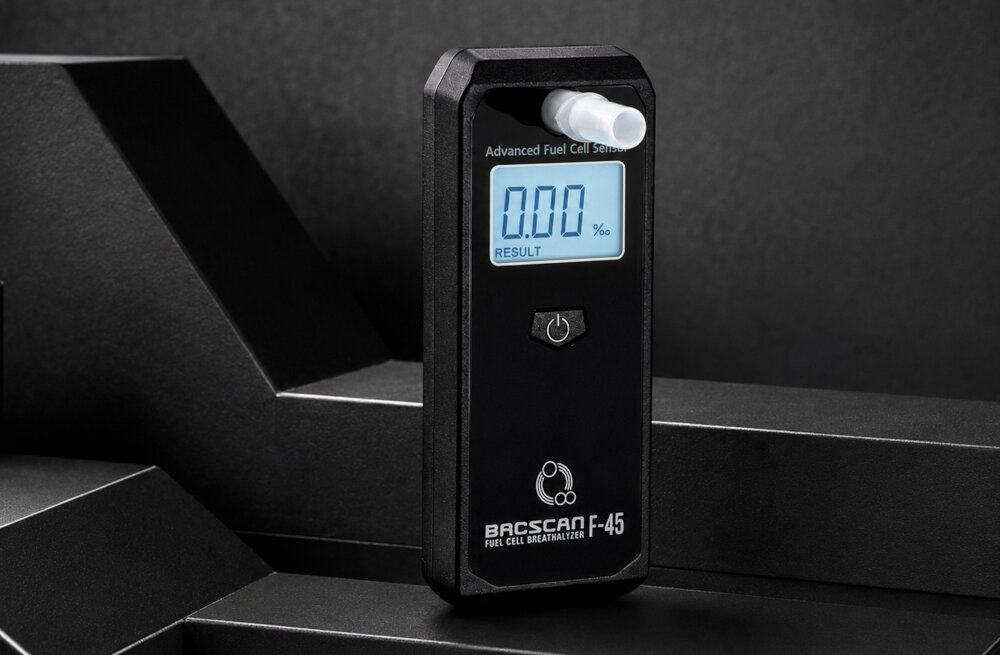 Alkomat BACSCAN F-45 Elektrochemiczny widoczny produkt na tle czarnych półek duży cyfrowy wyświetlacz wymiary 2,2 na 1,2 na 4,5 cm waga 82 gramy tworzywo ABS zasilanie 2 baterie AAA wyłączanie po 20 sekundach