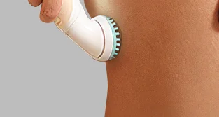 Kobieta używająca nakładki do masażu depilatora Braun na nodze – widok zbliżenia na gładką skórę.