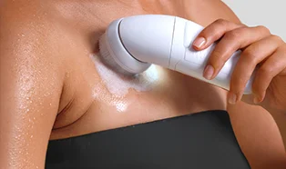 Kobieta używająca szczotki peelingującej do przygotowania skóry przed depilacją.