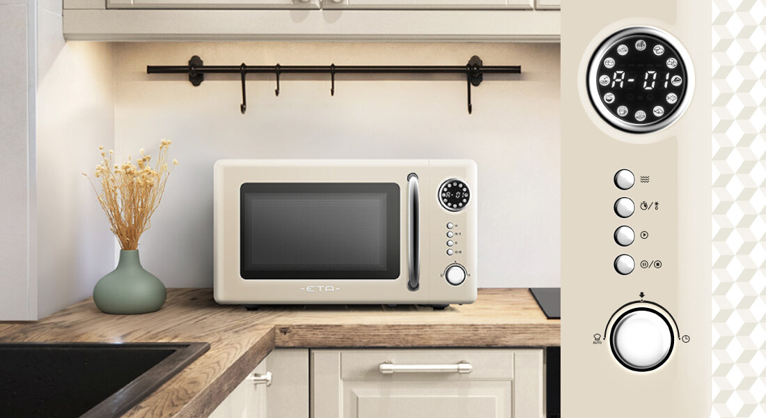 Beżowa kuchenka mikrofalowa z okrągłym wyświetlaczem i przyciskami znajduje się na blacie kuchennym. Obok widoczny jest zielony wazon z suszonymi kwiatami.