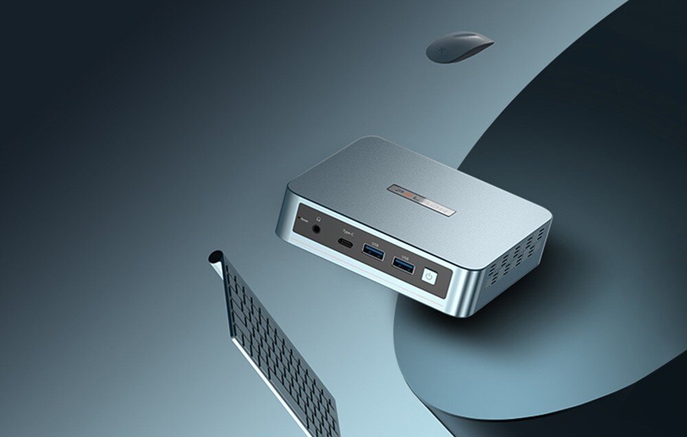 Komputer PELADN WI-6 N95 Widok z góry na jasnoniebieski mini komputer z logo na górnej obudowie, umieszczony na ciemnym, artystycznym tle obok krawędzi klawiatury