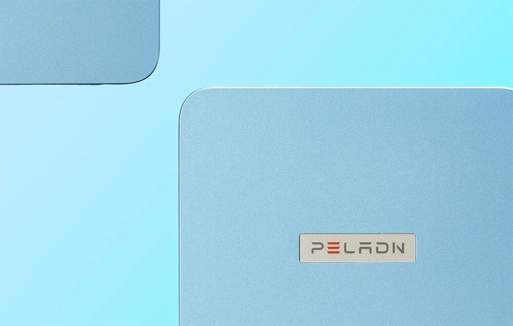 Komputer PELADN WI-6 Zbliżenie na górną część obudowy urządzenia w kolorze błękitnym o metalicznej strukturze z centralnie umieszczonym logotypem 'Peladn' w srebrnej ramce
