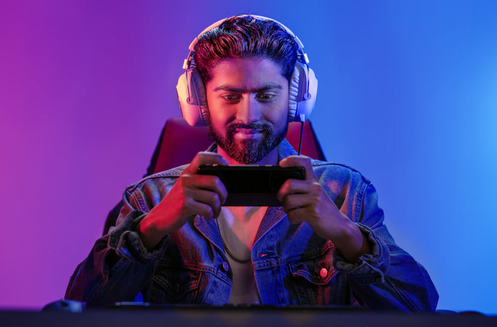 Karta pamięci SANDISK Gameplay MicroSDXC 1TB mężczyzna grający w grę na telefonie w pokoju szybki odczyt 190 MB/s dla płynnej rozgrywki