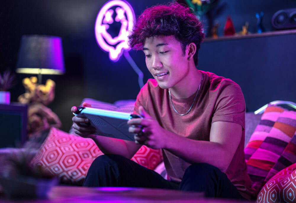 Karta pamięci SANDISK Gameplay MicroSDXC 1TB chłopak grający w grę na konsoli w pokoju na kanapie szybki zapis 130 MB/s do nagrywania 4K UHD