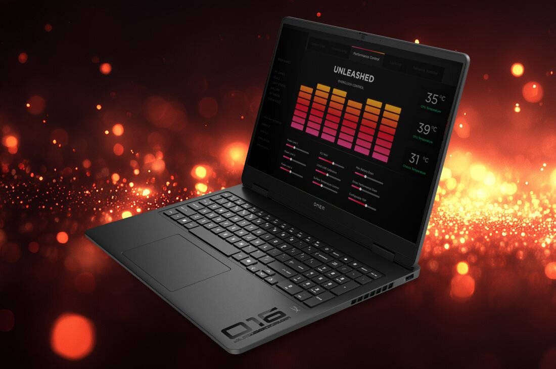 Laptop z otwartym ekranem wyświetlającym kolorowe wykresy i temperatury: 35°C, 39°C, 31°C. W tle widoczne są rozmyte, pomarańczowe światła.