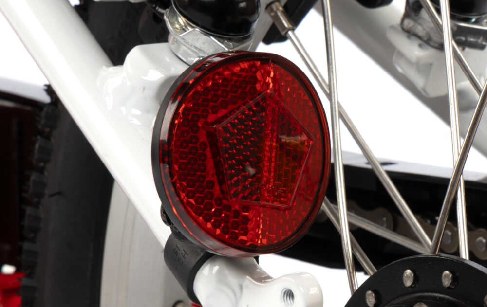 Rower dziecięcy KARBON Superlight Automatic 16 cali dla chłopca Czerwony białe tło zbliżenie na odblask umieszczony na ramie pod siodełkiem pakiet odblasków umieszczonych w kluczowych miejscach konstrukcji rowerek staje się lepiej widoczny po zmroku i w pochmurne dni wsparcie bezpieczeństwa odblaski zwiększają dostrzegalność dziecka