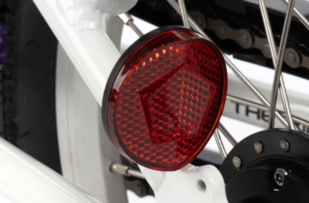 Rower dziecięcy KARBON Superlight Automatic 16 cali dla dziewczynki Różowy białe tło zbliżenie na odblask umieszczony na ramie pod siodełkiem pakiet odblasków umieszczonych w kluczowych miejscach konstrukcji rowerek staje się lepiej widoczny po zmroku i w pochmurne dni wsparcie bezpieczeństwa odblaski zwiększają dostrzegalność dziecka