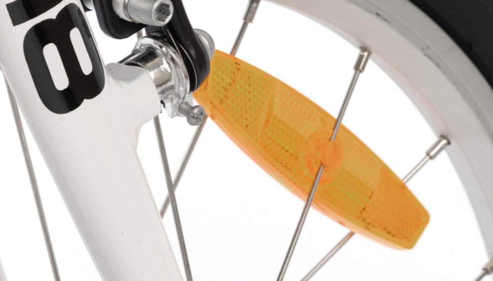 Rower dziecięcy KARBON Superlight 18 cali dla chłopca Czerwony białe tło zbliżenie na odblask umieszczony na szprychach pakiet odblasków umieszczonych w kluczowych miejscach konstrukcji rowerek staje się lepiej widoczny po zmroku i w pochmurne dni wsparcie bezpieczeństwa odblaski zwiększają dostrzegalność dziecka