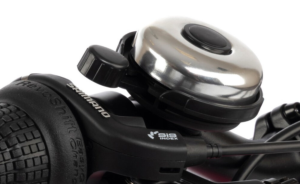 Zbliżenie na dzwonek rowerowy oraz manetkę zmiany biegów z widocznym napisem \'Shimano\' i \'SIS INDEX\'.