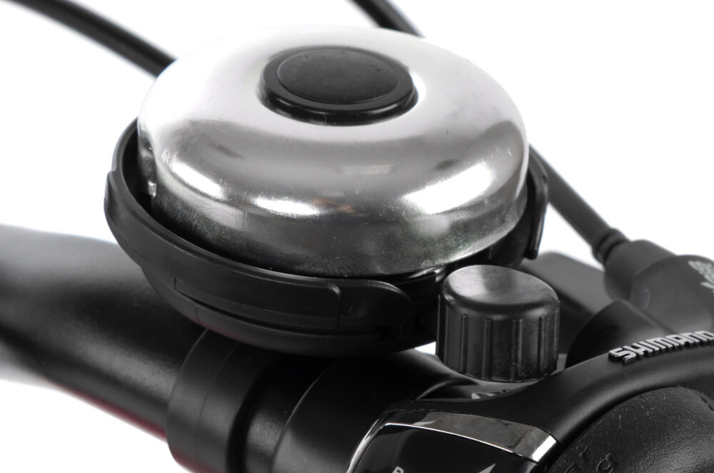 Rower młodzieżowy KARBON Superlight 24 cale dla dziewczynki Różowy białe tło zbliżenie na dzwonek praktyczny dzwonek sygnalizowanie obecności element zwiększający bezpieczeństwo