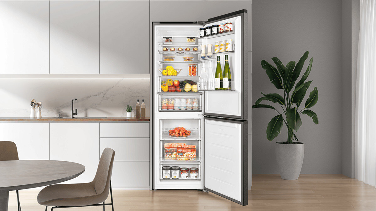 LODÓWKA TCL RC340BXC0EU W jasnej kuchni otwarta lodówka prezentuje starannie ułożone produkty na półkach. Wnętrze jest jasne i pojemne, podkreślając dużą wydajność urządzenia funkcjonalne wnętrze lodówki szuflady balkoniki przestronne półki wygoda korzystania