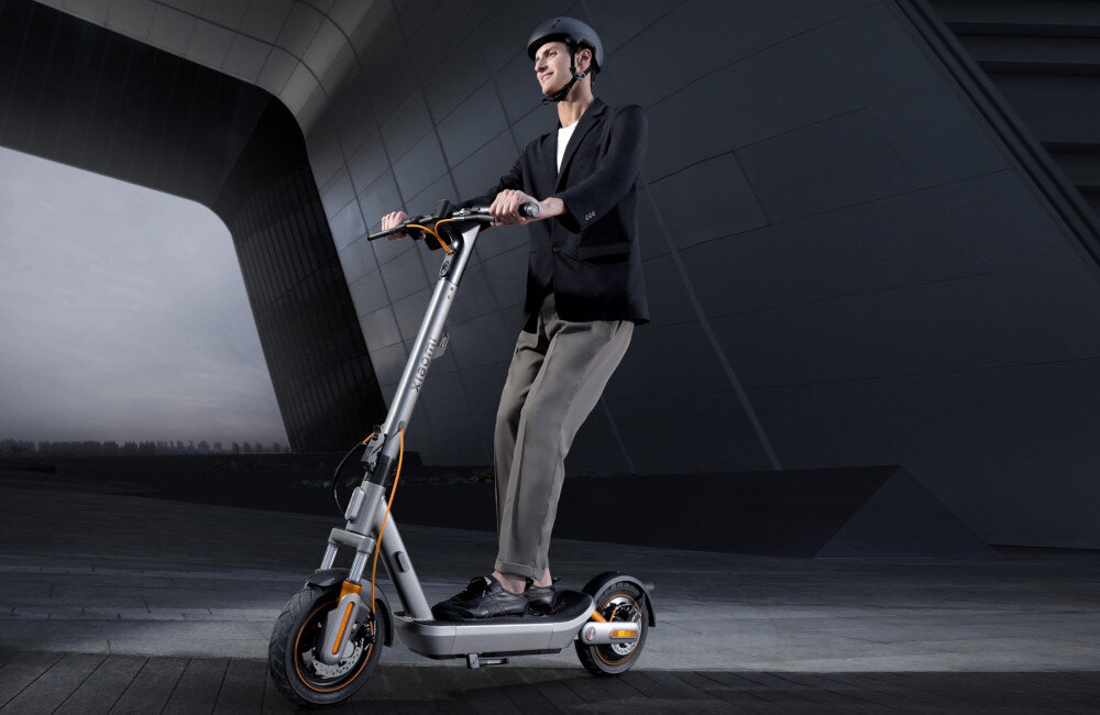 Hulajnoga elektryczna XIAOMI Electric Scooter 6 Max Max 70km 450W 2 amortyzatory 12 cali Czarny ciemne tło osoba jedzie na hulajnodze po drodze przednie światło o mocy 2,5 W bardzo dobra widoczność w ciemności (nawet do 15 metrów) wbudowane kierunkowskazy tylne światło stopu bezpieczeństwo