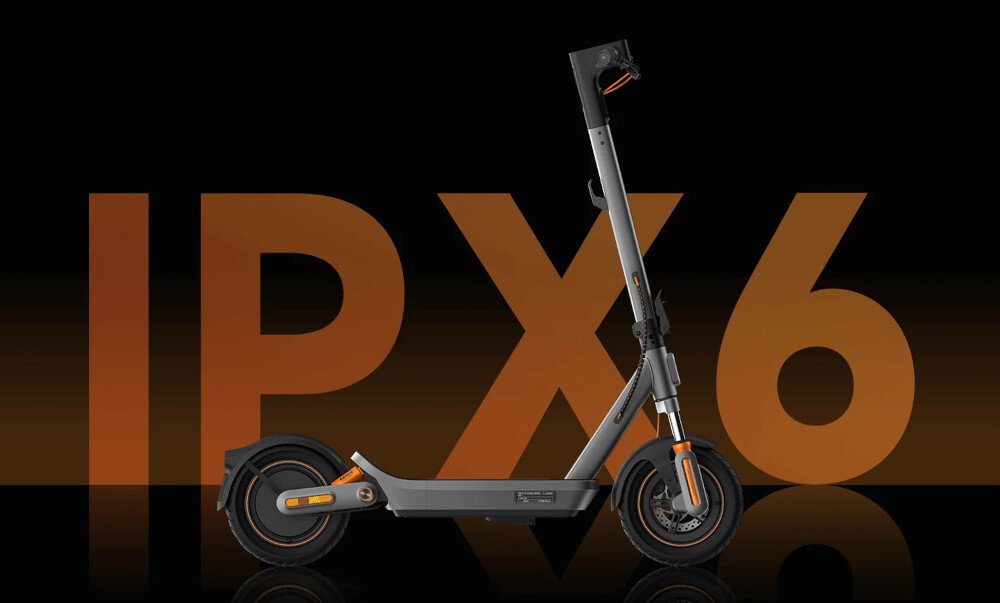 Hulajnoga elektryczna XIAOMI Electric Scooter 6 Max Max 70km 450W 2 amortyzatory 12 cali Czarny ciemne tło pomarańczowy napis IPX6 na tle napisu stoi hulajnoga klasa wodoodporności IPX6 ochrona całego układu elektrycznego przed silnymi strumieniami wody i intensywnym deszczem uszczelnione połączenia zabezpieczone komponenty sprzęt sprawdza się podczas jazdy po mokrej nawierzchni, kałużach i w zmiennych warunkach pogodowych