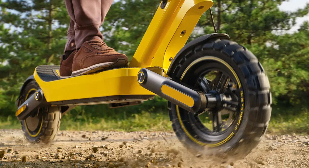 Hulajnoga elektryczna XIAOMI Electric Scooter 6 Ultra 75km 500W 2 Amortyzatory 12 cali Żółty las osoba jedzie na hulajnodze po piasku koła bezdętkowe o średnicy 12 cali szerokość 3 mm niski opór toczenia duża przyczepność do podłoża bardzo dobrze absorbują wstrząsy i nierówności terenu opony są odporne na przebicia i nie wymagają konserwacji