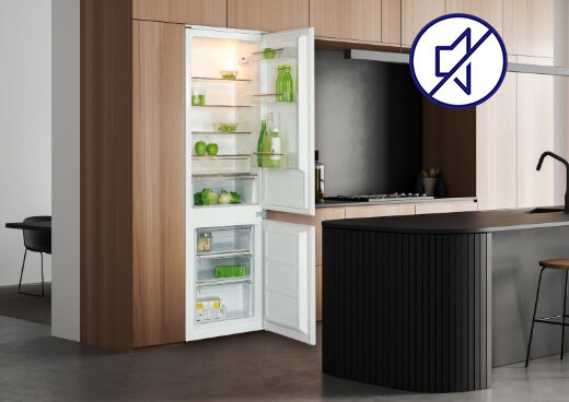 Lodówka MPM-259-KBI-16/E z otwartymi drzwiami w zabudowie kuchennej. Ikona przekreślonego głośnika.