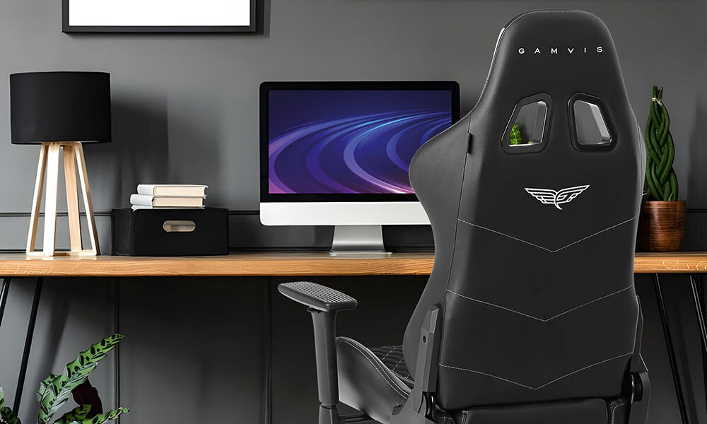 Fotel GAMVIS Phantom Large Czarny (białe elementy) prezentacja fotela w ciemnym pokoju przy biurku monitor kwiatek lampka akcesoria wyścigowy charakter elegancja fotel klasy premium niezliczone godziny przed ekranem