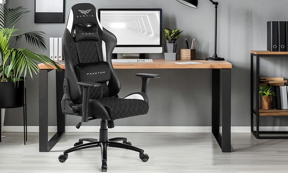 Fotel GAMVIS Phantom Large Czarny (białe elementy) prezentacja fotela na tle pokoju biurowego w tle biurko z monitorem i akcesoriami kwiatek obok regał szara ściana wielozadaniowy komfort biuro