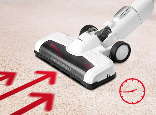 Na obrazie widoczny jest biały odkurzacz na dywanie z czerwonymi strzałkami wskazującymi kierunek oraz ikoną zegara. Na odkurzaczu znajduje się logo \'Amica\'.