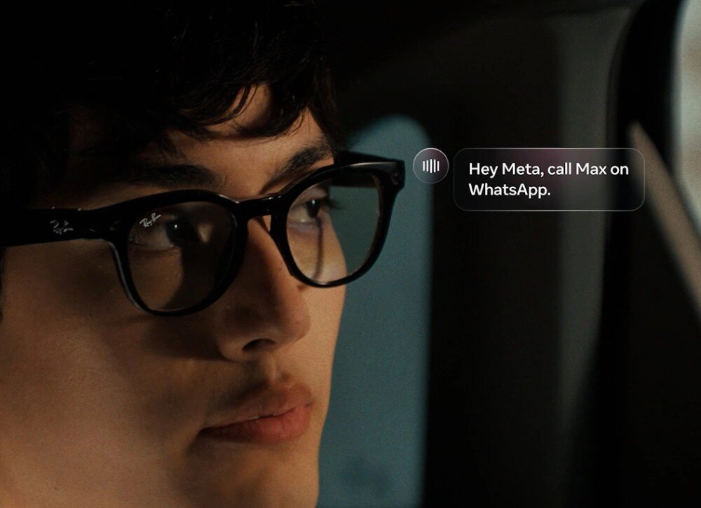 Okulary META Ray-Ban Wayfarer Gen 2 zbliżenie na twarz mężczyzny w czarnych okularach, obok których unosi się półprzezroczyste okno dialogowe z ikoną fali dźwiękowej i napisem 'Hey Meta, call Max on WhatsApp'