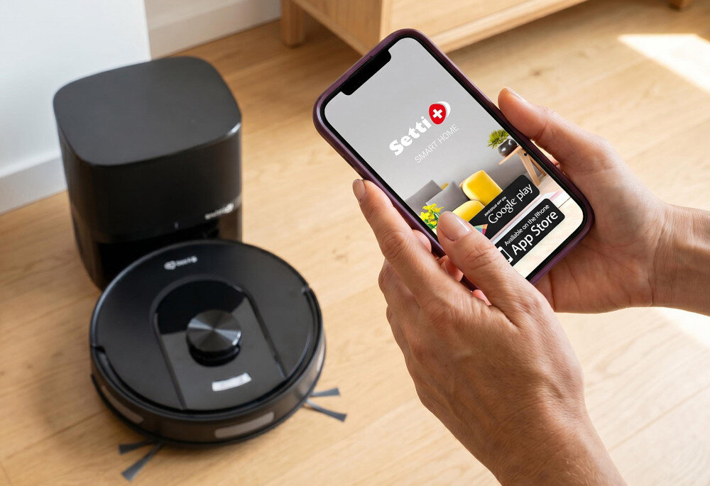 Robot sprzątający SETTI+ RV600S pokój osoba trzyma w dłoniach telefon w tle robot i stacja dokująca połączenie Wi-Fi i Bluetooth aplikacja SETTI+ z poziomu urządzenia mobilnego częstotliwość opróżniania pojemnika na kurz Lampki kontrolne