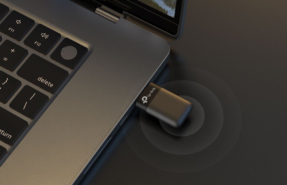 Karta sieciowa TP-LINK Archer TX23U Widok z góry na adapter wpięty do portu USB w laptopie z rozchodzącymi się od niego okręgami symbolizującymi zasięg sieci bezprzewodowej