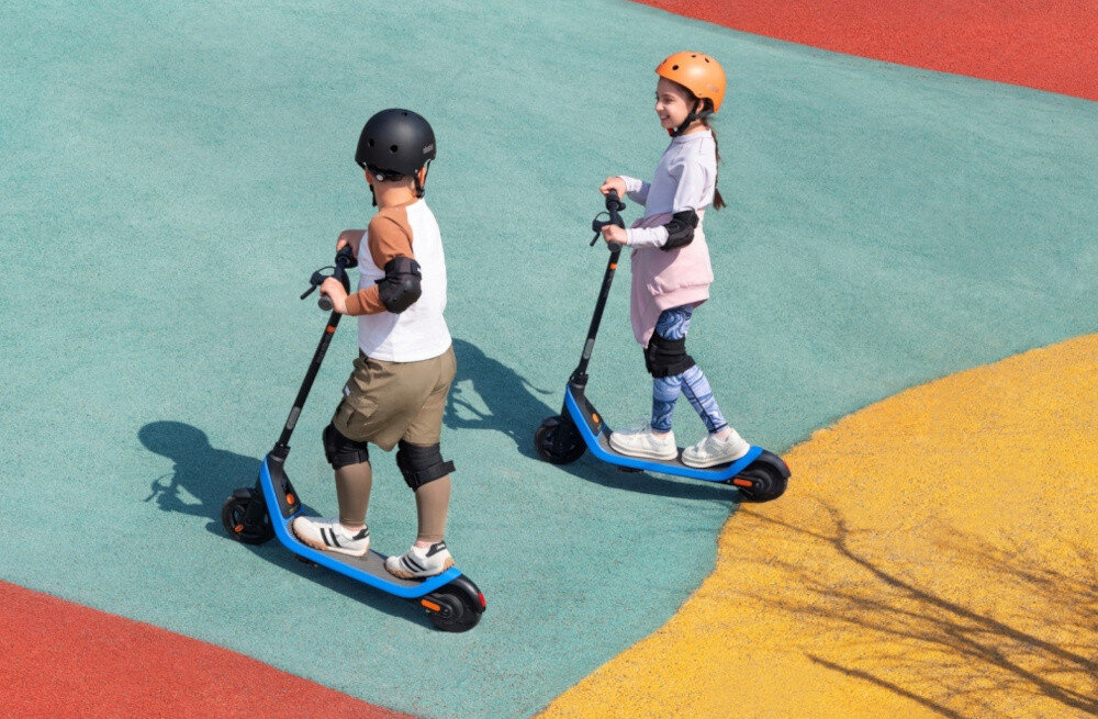 Hulajnoga elektryczna SEGWAY Ninebot C2 Lite 9km 130W 7 cali Czarno-niebieski skatepark kolorowa nawierzchnia dwójka dzieci jedzie na hulajnogach bezszczotkowy silnik o mocy wyjściowej 120 W maksymalna moc 130 W napędza tylne koło maksymalna prędkość do 16 km/h napęd tylnego koła przyczepność kontrola nad pojazdem efektywne wykorzystania energii