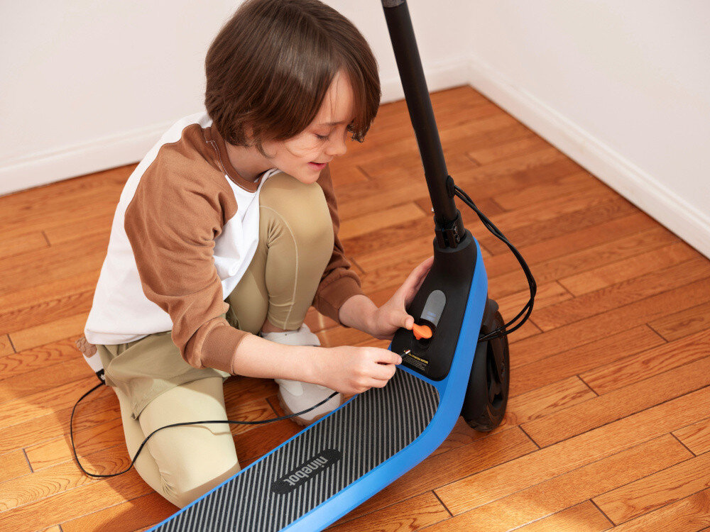 Hulajnoga elektryczna SEGWAY Ninebot C2 Lite 9km 130W 7 cali Czarno-niebieski pomieszczenie drewniana podłoga dziecko podłącza hulajnogę do ładowarki bateria o pojemności 2,55 Ah (56 Wh) zasięg do 9 km zasięg w trybie standardowym nawet do 14 km bateria litowo-jonowa o napięciu 21,6 V czas ładowania około 5,5 godziny łatwy do odczytania wskaźnik naładowania baterii