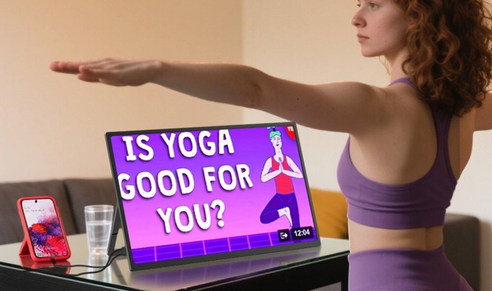 Monitor ZEUSLAP Z18S Kobieta w stroju sportowym ćwicząca jogę, przed nią na stole stoi monitor w orientacji poziomej z wyświetlonym filmem o jodze oraz smartfon podłączony kablem, przekątna, rozdzielczość, matryca IPS
