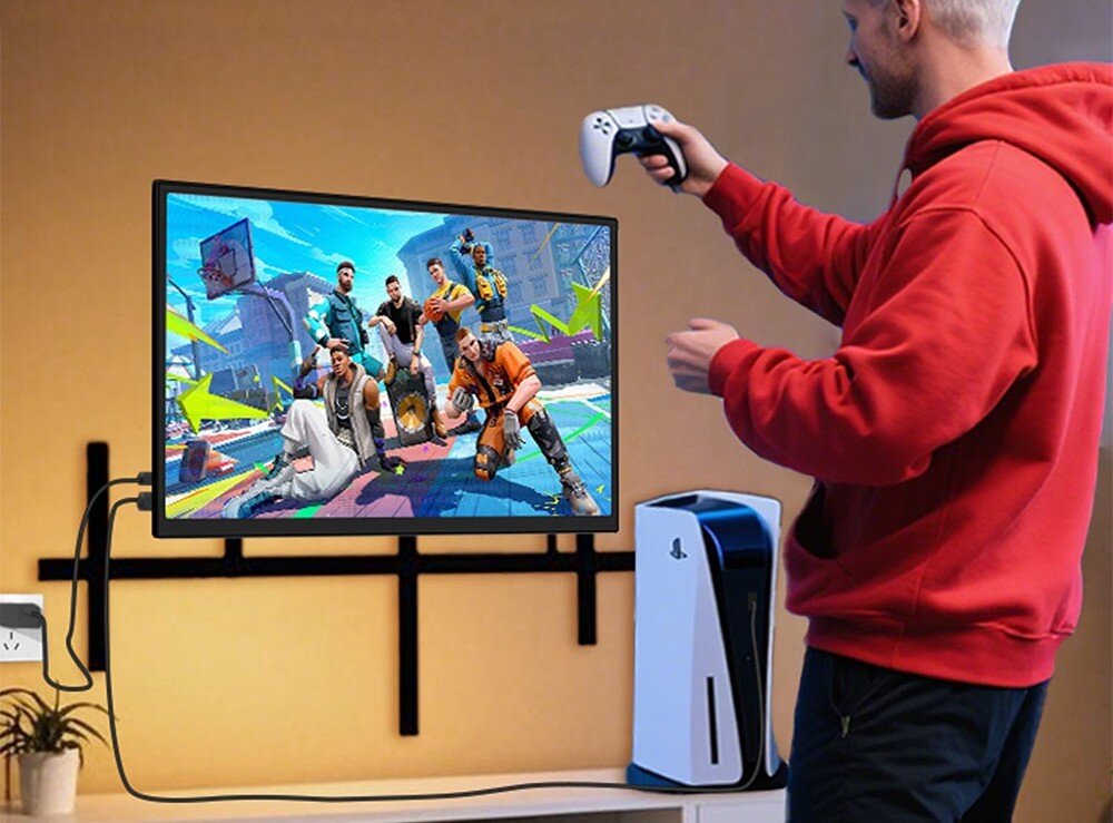 Monitor ZEUSLAP Z18S Mężczyzna w czerwonej bluzie grający na konsoli podłączonej do monitora zawieszonego na ścianie, na ekranie wyświetlana jest kolorowa gra sportowa, lekkość, zasilanie, regulacja pochylenia, montaż VESA