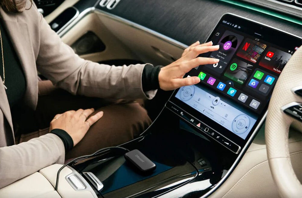 Adapter OTTOCAST CA515-T Play2Video Ultra CarPlay Android Auto bezprzewodowe CarPlay Android Auto niski czas opóźnienia multimedia USB, osoba siedząca w aucie używająca stacji multimedialnej