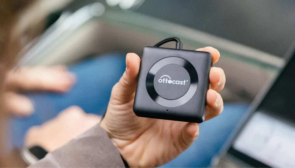 Adapter OTTOCAST CA361-C4 Car TV Mate CarPlay Android Auto HDMI przewodowa projekcja, osoba trzymająca adapter w ręku