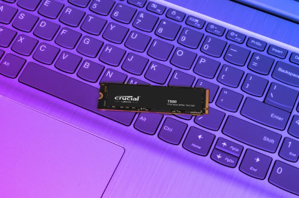 Dysk CRUCIAL T500 Cienki dysk SSD leży na klawiaturze laptopa z fioletowym podświetleniem, interfejs, zużycie energii, wydajność