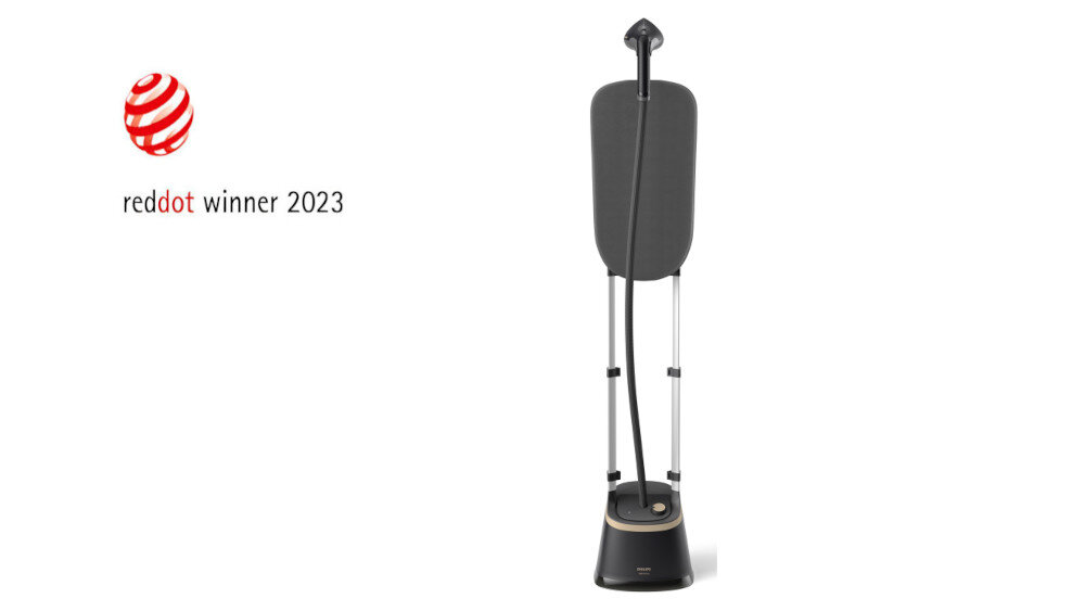 Na obrazie widoczna jest parownica do ubrań z ciemnym stojakiem i deską do prasowania. Obok znajduje się logo \'reddot winner 2023\'.