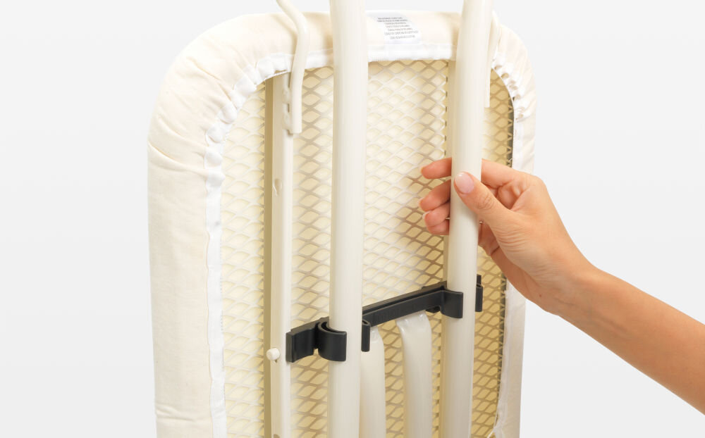 Deska do prasowania BRABANTIA 103629 Bubbles 124 x 38 cm osoba trzyma złożoną deskę biała metalowa konstrukcja białe tło wygodne przechowywanie i transport blokada transportowa bezpieczne złożenie blokada dziecięca zapobieganie przypadkowemu otwarciu dodatkowe bezpieczeństwo w domu łatwa do przechowywania małe przestrzenie 