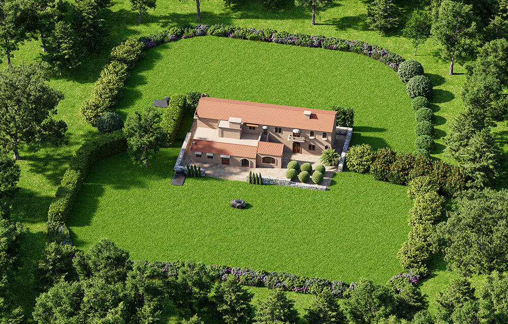 Widok z lotu ptaka na duży dom otoczony zielonym trawnikiem i drzewami. Na trawniku znajduje się mały, ciemny obiekt, prawdopodobnie robot koszący.