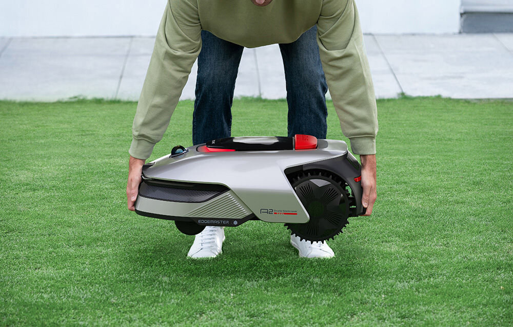 Robot koszący DREAME A2 1200 ogród trawnik osoba podnosi robota w tle taras monitorowanie otoczenia w czasie rzeczywistym uruchamianie trybu patrolowania poza godzinami koszenia wysyłanie powiadomień w przypadku wykrycia aktywności człowieka system alertów podnoszenia wysyła powiadomienie w aplikacji emituje dźwięk ostrzegawczy