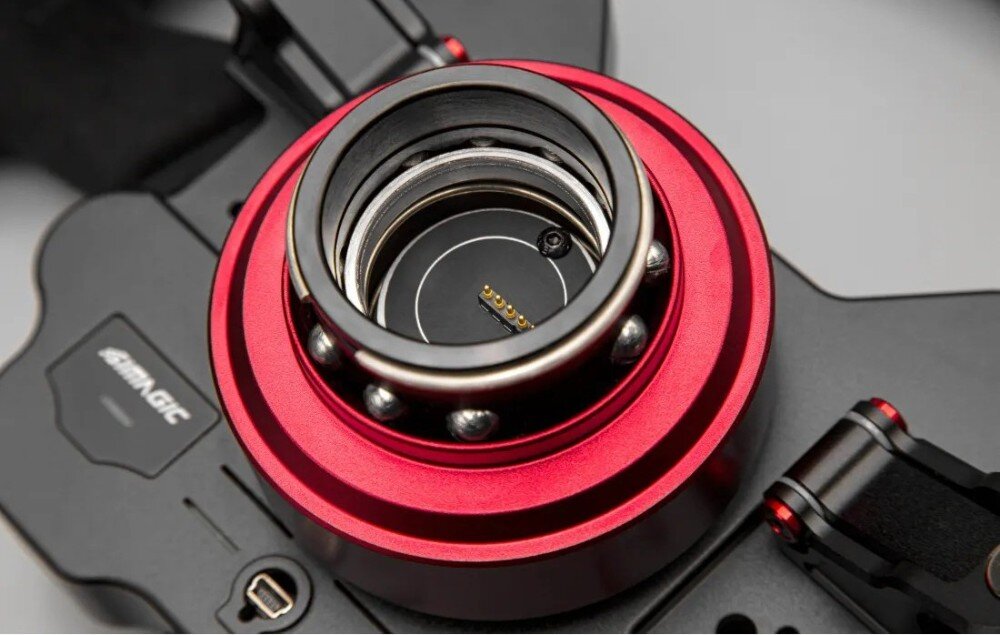Kierownica SIMAGIC GT1 D-shape QR70 Zbliżenie pod kątem na metalowy mechanizm szybkiego montażu z widocznymi łożyskami kulkowymi i pinami stykowymi wewnątrz otworu
