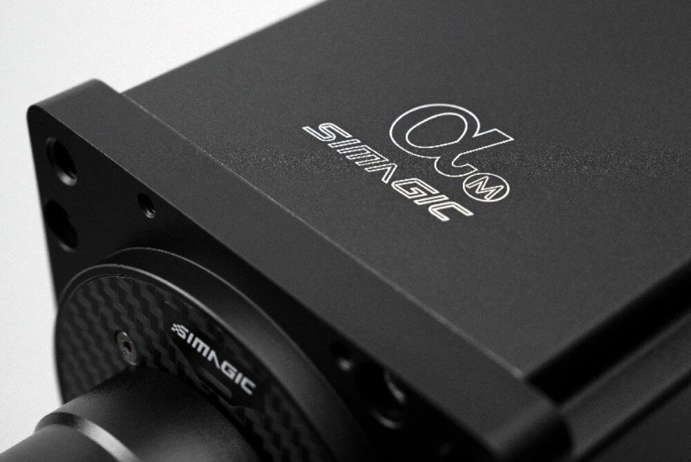 Baza kierownicy SIMAGIC Alpha 15 Nm Direct Drive S102 Zbliżenie na górną obudowę metalowej bazy z widocznym białym napisem 'Alpha M' oraz mniejszym logo poniżej