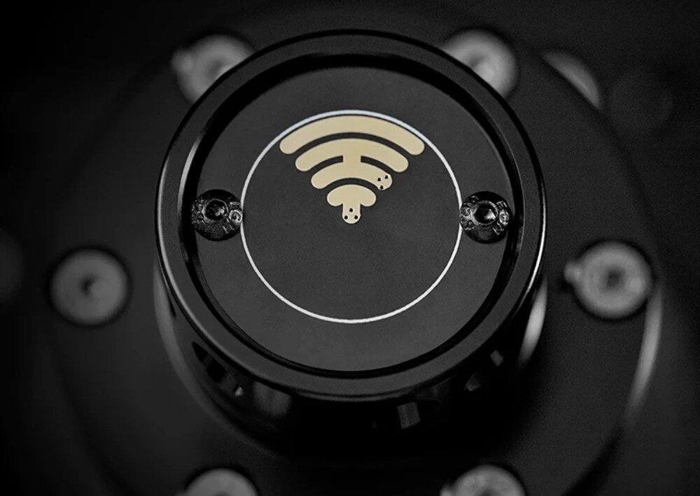 Baza kierownicy SIMAGIC Alpha Mini 10 Nm Direct Drive S101 Zbliżenie na okrągły przód wału montażowego z symbolem fali bezprzewodowej pośrodku i dwoma śrubami po bokach